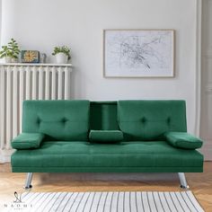 a green futon sofa sitting on top of a hard wood floor next to a radiator