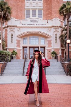 a woman in a graduation gown and cap is posing for a photo outside the university