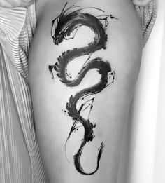 a black and white photo of a woman's thigh with a dragon tattoo on it