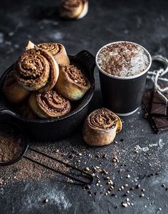 cinnamon rolls in a pan next to two cups of coffee