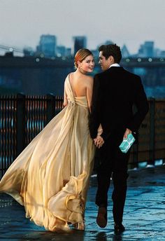 a man and woman are walking down the street together, dressed in evening gowns