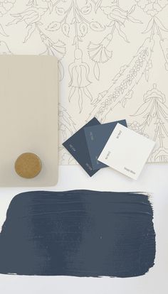 some paint samples are sitting on a table next to a wallpaper with blue and white designs