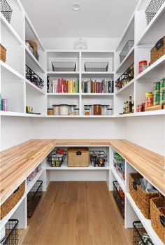 an organized pantry with white shelves and wooden floors