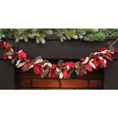 a christmas garland hanging from the fireplace with red and white ribbons on it's mantle