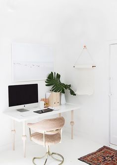 a white desk with a computer on it and a plant in the corner next to it