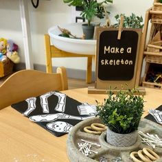 there is a potted plant on the table with cookies in front of it and a sign that says make a skeleton