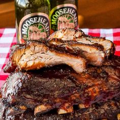 two bottles of booze next to some ribs on a red and white checkered table cloth