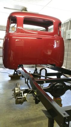 an old red car being worked on in a garage