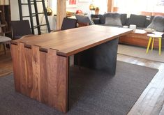 a large wooden table sitting in the middle of a living room next to a couch