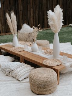 the table is set with white vases and place mats