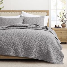 a bed with grey bedspread and pillows