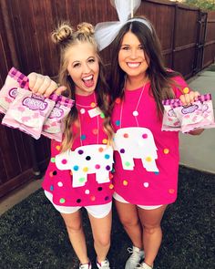 two girls in matching pink outfits holding up bags