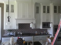 a kitchen with white cabinets and black counter tops