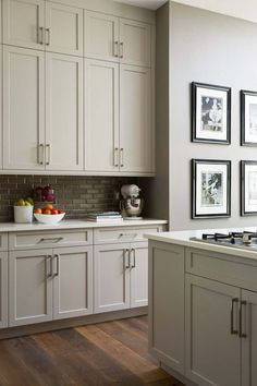 a kitchen with white cabinets and pictures on the wall above the stove top is shown