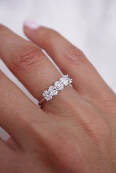 a woman's hand wearing a three stone diamond ring