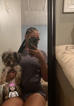 a woman taking a selfie with her dog in front of a mirror while holding a cell phone