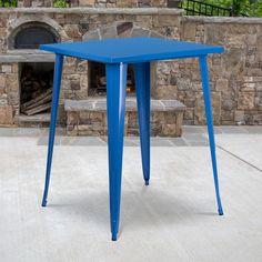 a blue table sitting on top of a cement floor next to a brick wall and fire place