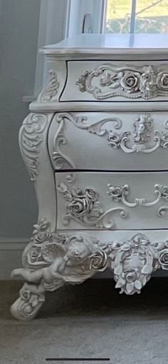 an ornate white dresser in front of a window