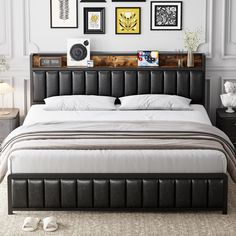 a bed with white sheets and black headboard in front of pictures on the wall