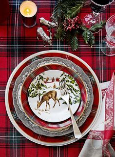 a christmas table setting with plates, napkins and silverware on a red plaid table cloth