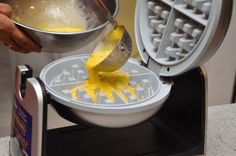 a person pouring yellow liquid into a waffle maker