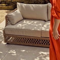 a woman in an orange dress is standing next to a couch with pillows on it