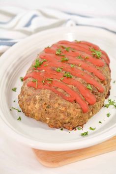 a meatloaf covered in ketchup on a white plate with a wooden spoon