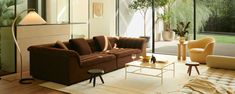 a living room filled with furniture next to a large glass wall window covered in greenery