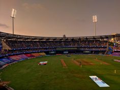 an empty stadium filled with lots of people watching a baseball game at sunset or dawn