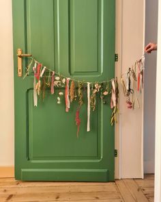 a green door with clothes hanging from it's side and a hand holding a string