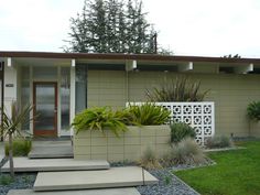 a house with plants in the front yard and steps leading up to it's entrance