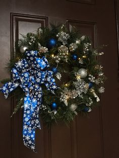 a wreath with blue and silver ornaments hanging on a door