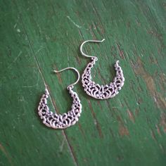 This is a larger size, sandcast arracada Mexican earring. It is the traditional arracada or crescent shape, so common on the earlobes of Mexican women, with a small flowers and leaves. They are 92.5% silver or sterling silver. It has a slight patina from oxidation to make them appear old. Handmade near Mexico City. Each earring is slightly different from the photo--they are handmade so there is a little variation in how close the flowers are to the edges. Arracada earrings naturally sit slightly Crescent Jewelry With Intricate Design, Traditional Silver Crescent Earrings, Silver Crescent Filigree Jewelry, Traditional Crescent Shaped Pierced Earrings, Fiesta Party Decorations, Mexican Earrings, Mexican Women, Crescent Shape, Fiesta Party