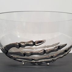 a glass bowl with metal handles on a table