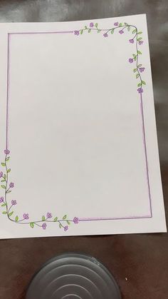 a white paper with purple flowers and green leaves on it next to a gray object