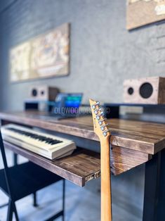 an electric guitar resting on top of a wooden table next to a keyboard and speakers