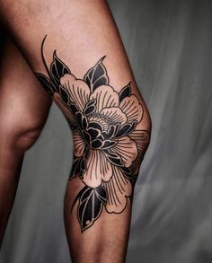 a woman's leg with black and white flowers on it, in front of a gray background