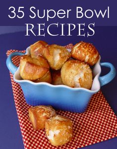 a blue bowl filled with croissants on top of a red and white checkered cloth