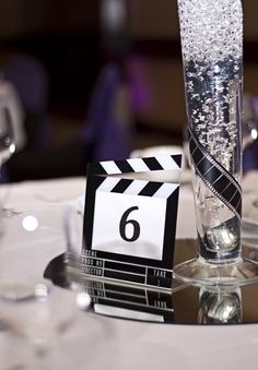 a close up of a glass on a table with a movie claper in it