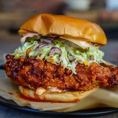 a fried chicken sandwich with coleslaw and slaw on a black platter