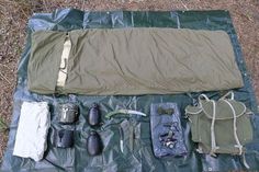 the contents of an outdoor survival kit laid out on a tarp in the grass