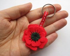 a hand holding a red felt flower keychain