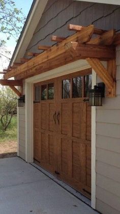 a garage with two brown doors and a wooden pergolated roof over the door