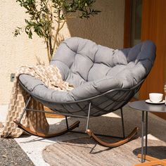 a rocking chair sitting on top of a rug next to a table and potted plant