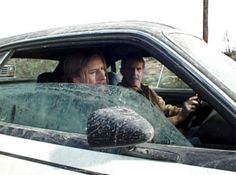 two people sitting in a car looking at something