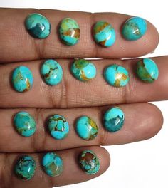 a person's fingers with turquoise and gold painted nails