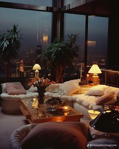 a living room filled with lots of furniture next to large windows overlooking the city at night