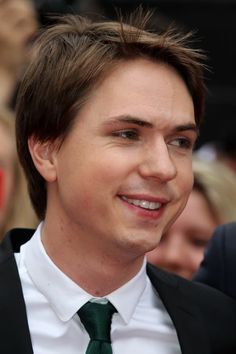 a close up of a person wearing a suit and tie with people in the background