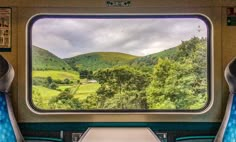 the inside of a train car looking out at mountains and fields from it's windows