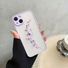 a woman is holding up her phone case with flowers on the front and back cover